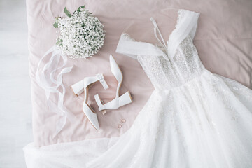 Wedding dress shoes and rings lie on the bride's bed.
