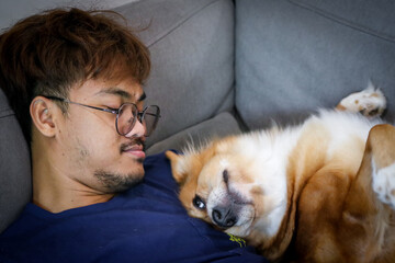 A man and a dog relax sleeping with the owner together on sofa couch in living room home interior background.