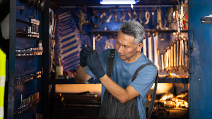 Fototapeta na wymiar Portrait senior asian male mechanic engineering working on tools box background. Repair specialist, technical maintenance. Small business owner.
