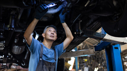 senior asian male mechanic engineering working under Vehicle in Car Service. Repair specialist,...