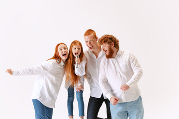Happy family, redheaded young men, woman and kid wearing casual style clothes spend time together at studio photo shoot.