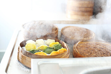 Cooking colorful dumplings in a bamboo steamer baskets. Traditional dim sum, Chinese dumplings on steam.