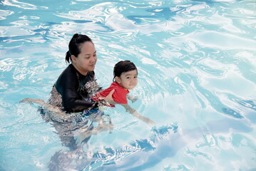 Mother teach her son to swim in swimming pool