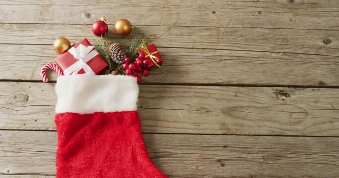 Video of christmas gifts in christmas stocking and copy space on wooden background