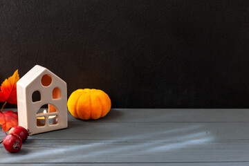 Halloween. On a black and gray background are a house, pumpkin and small apples