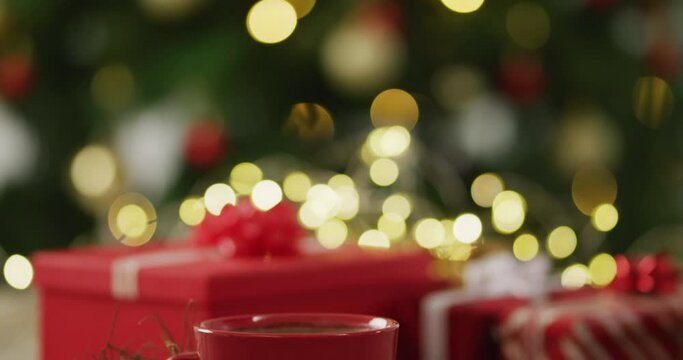 Video of christmas gift and hot chocolate over christmas tree and lights