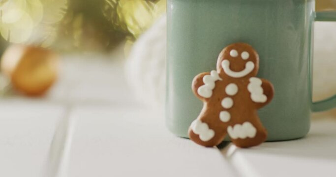 Video of gingerbread men and hot chocolate over christmas tree and lights