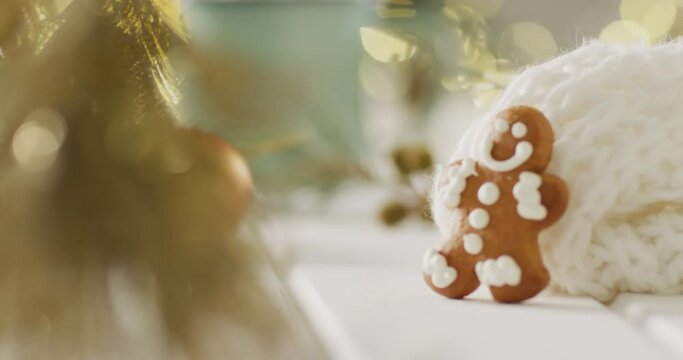 Video of gingerbread men and hot chocolate over christmas tree and lights