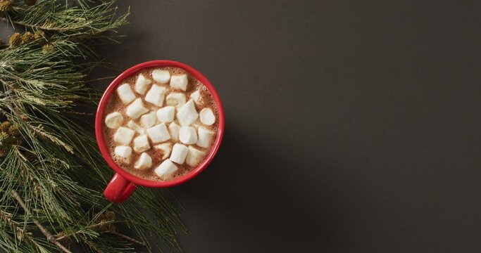 Video of cup of hot chocolate with marshmallows and warm blanket over black background
