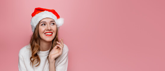Close up portrait of young happy smiling woman in santa hat isolated on pink background in studio