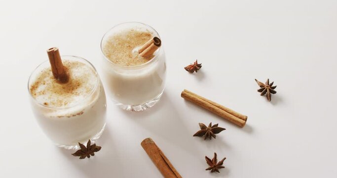 Video of cups of hot chocolate with cinnamon over white background