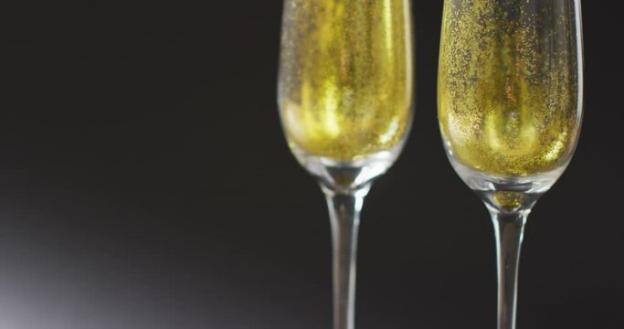 Video of two full champagne flute glasses on black background, with copy space