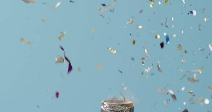 Video of exploding party popper and falling confetti on blue background