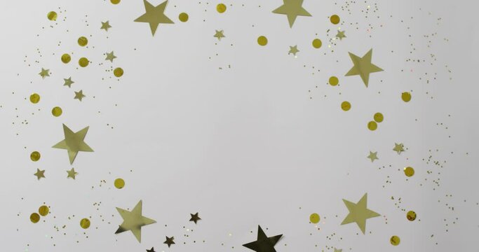 Video of gold and silver star and circle confetti on white background with central copy space