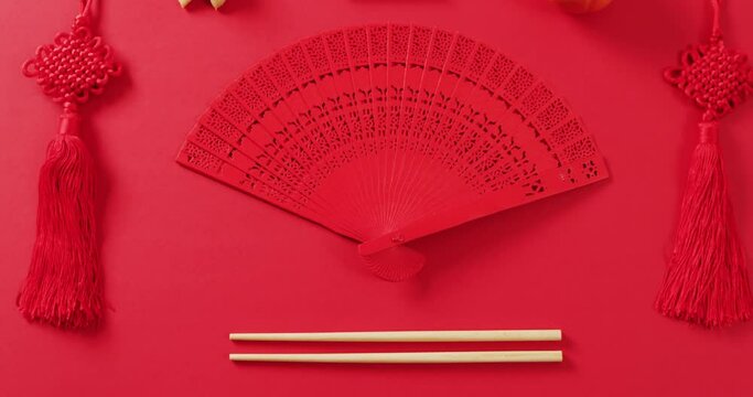 Video of close up of chinese fan and decorations on red background