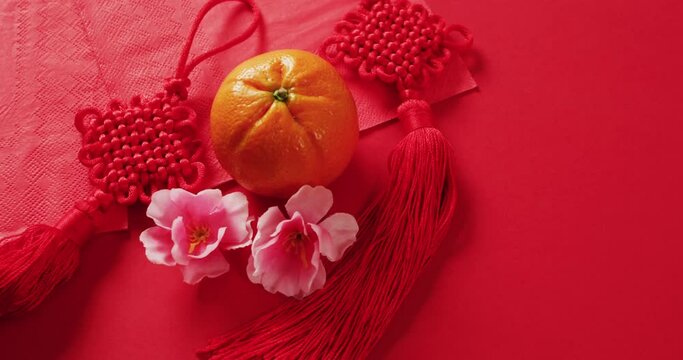 Video of close up of orange and decorations on red background