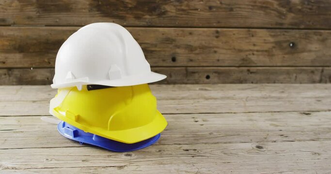 Video of close up of colourful building helmets on wooden background