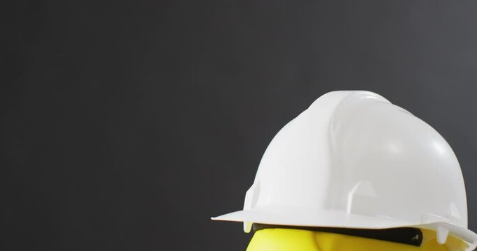 Video of close up of colourful building helmets on gray background
