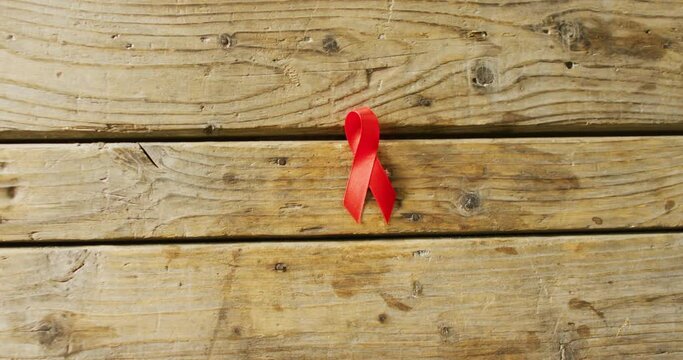 Video of close up of red cancer ribbon on wooden background