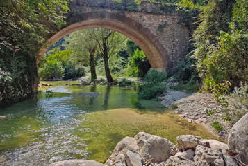Historical stone bridge over a wild river in the Italian alps.