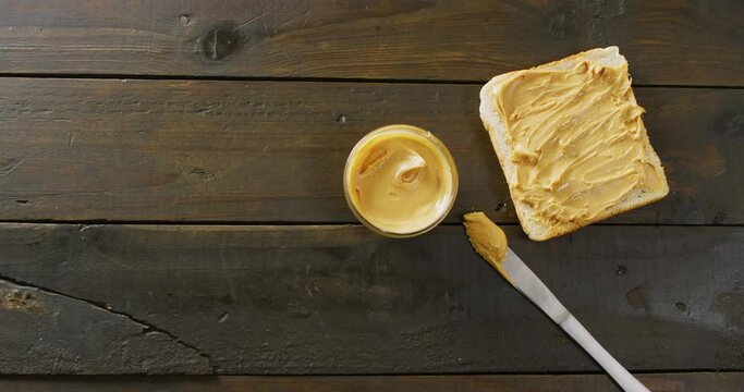 Video of close up of toast with peanut butter on wooden background