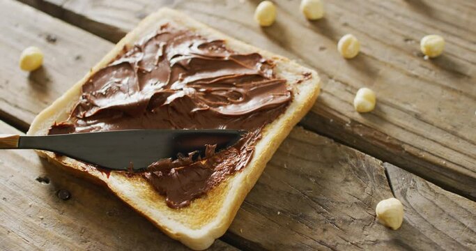 Video of close up of toast with chocolate cream on wooden background