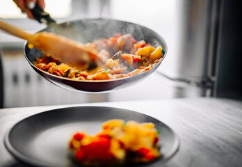 woman puts food from a frying pan into a plate