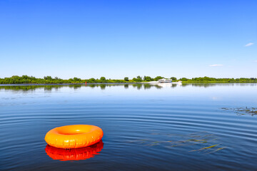 An orange inflatable swim ring. Summer rest. River boats