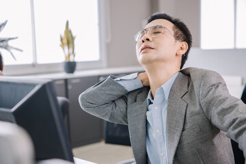 A businessman who works in the office looks tired and stressed by pressing her hands