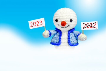 snowman with sign with inscription 2022 and 2023, on blue background, new year concept