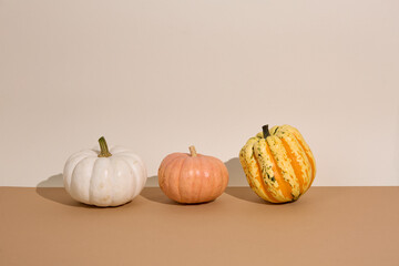 white, red and yellow pumpkins for Halloween on cream and brown geometric background