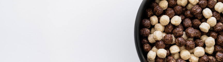 top view of cereal balls with chocolate and vanilla flavors in bowl isolated on white, banner.