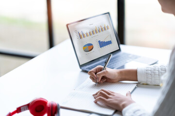 Cropped shot of Asian woman hand using laptop and writing making list taking notes in notepad working or learning on laptop  educational course or training, education online concept