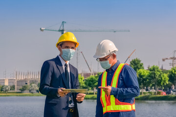 Asian team Construction engineers supervising progress of construction project stand on new factory, Engineering Consulting People on construction site Building inspector.