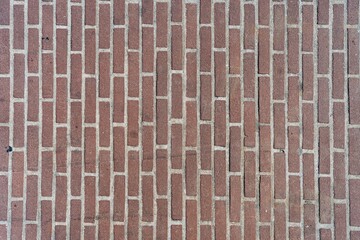 Red brick pattern. Old brick wall with cracks and scratches. Vertical wide brickwall background. Distressed wall with broken bricks texture. Vintage house facade.