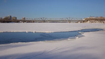 Frozen Ottawa river with Alexandra bridge ad Nepean point on a sunny winter day with clear blue sky. Ottawa, Ontario, Canada