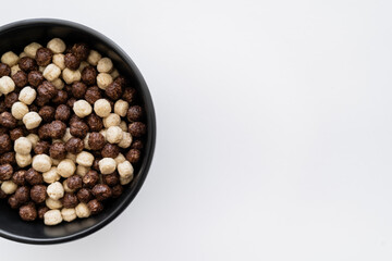 top view of cereal balls with chocolate and vanilla flavors in bowl isolated on white.