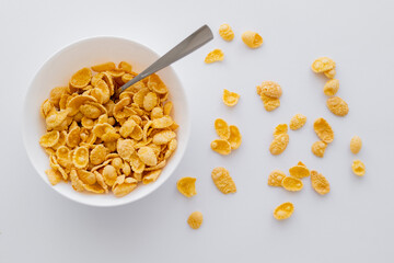 top view of bowl with crispy corn flakes and spoon isolated on white.