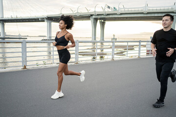 Athletic people in sportswear are engaged in fitness, runners are training. A man and a woman are running.