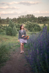 Photo of a girl with a basket among blue flowers.