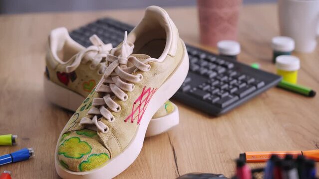 shoes design, modern trend to update used shoes, exclusive print sneakers painted by designer stand on table, close-up