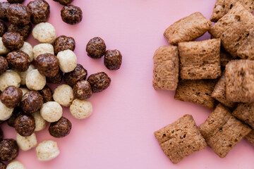 top view of various breakfast cereal puffs and balls isolated on pink.