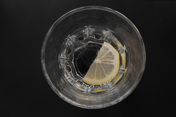 Summer refreshing drink on the rocks with lemon slice . View from above on dark background