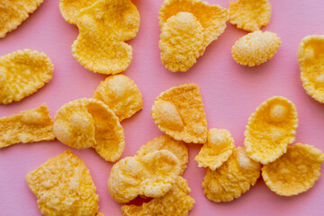top view of tasty and yellow corn flakes on pink background.