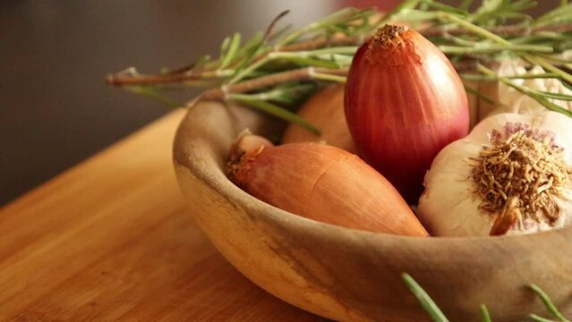 fresh raw onions, garlic, rosemary close up in wooden bowl