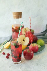 Detox drink from apples, berries, mint and citrus in glasses and in a decanter, on the table, seasonal drinks from organic natural ingredients
