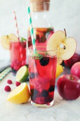Detox drink from apples, berries, mint and citrus in glasses and in a decanter, on the table, seasonal drinks from organic natural ingredients