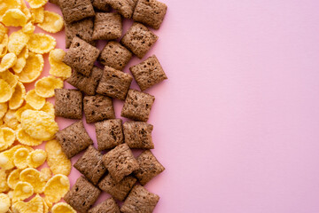 flat lay of breakfast cereal puffs and crispy corn flakes isolated on pink.