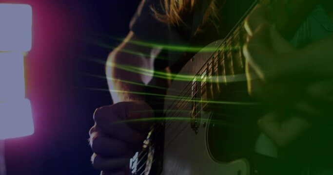 Animation of green light trails over slow motion hand of musician playing electric guitar