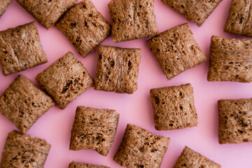 top view of breakfast cereal puffs with chocolate isolated on pink.